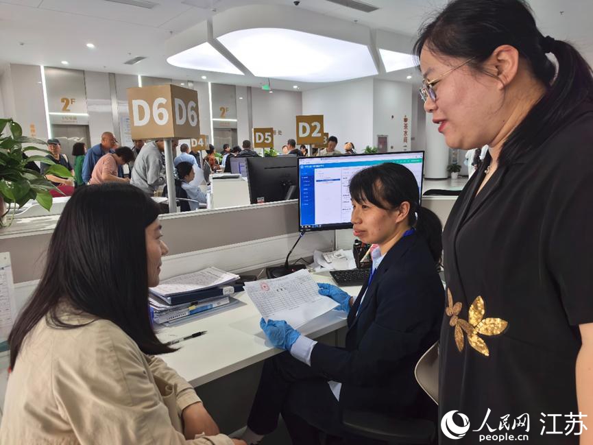 海安市人社局副局长施佳男(右)协助企业办事员办理参保手续。人民网记者 王继亮摄