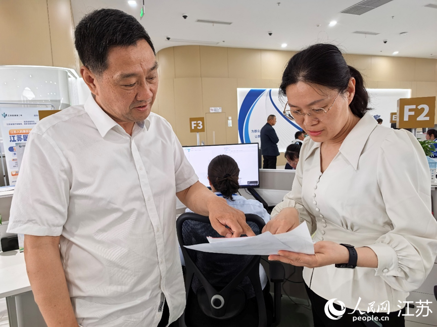 海安市医保局副局长陆晓静(右)协助群众办理医保报销。人民网记者 王继亮摄